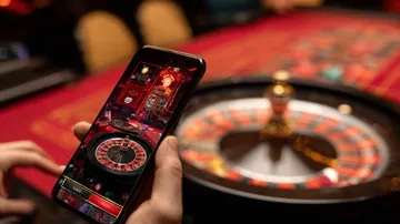 উৎসবের মুহূর্তে ঐতিহ্যবাহী পোশাক পরা এক আনন্দিত নারী তার স্মার্টফোন ব্যবহার করছেন, যা দেখায় 456BD অ্যাপ কীভাবে দৈনন্দিন জীবনের সঙ্গে সহজে মানিয়ে যায়।